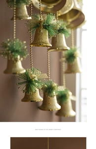 Detail of gold Christmas bell ornaments featuring green pine needles and golden bows