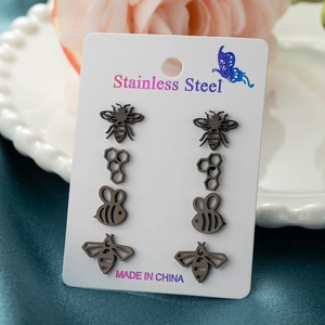 Detailed macro view of four pairs of black stainless steel bee and honeycomb stud earrings