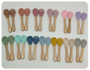Flat lay of colorful food-grade silicone baby spoons and forks with wooden handles