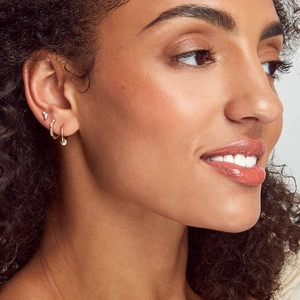 Close-up of elegant gold s925 silver hoop earrings with diamond and pearl pendant set