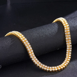Golden double-row rhinestone tennis chain displayed on a professional black textured stand