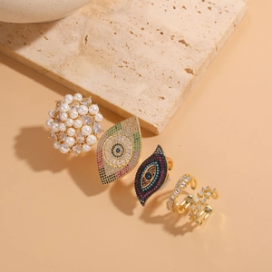 Detailed set of four luxury rings featuring pearl, zircon evil eye, and row diamond designs