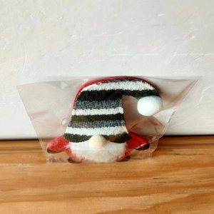 Close-up of a Christmas gnome cutlery holder with a striped hat in clear packaging