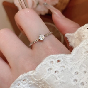 Close-up of elegant silver twist band ring featuring a single sparkling diamond on finger