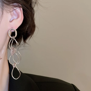 Close-up of layered silver geometric tassel earrings worn to show the stylish drop design