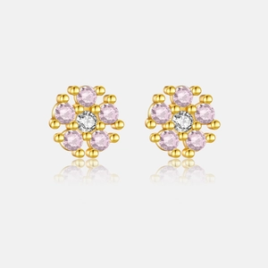 Detailed macro view of gold flower earrings with pink gemstones and white center stone