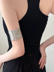 Detail of silver multi-layer wire arm cuff bracelet worn by model on upper arm