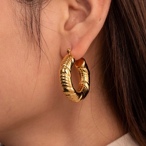 Elegant gold twisted croissant hoop earrings worn by a model in a minimalist style