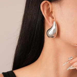Close-up of metallic silver water drop earring with high-gloss mirror finish on model
