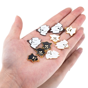 DIY ghost charms in black and white enamel with gold edges shown on a hand palm