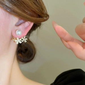 Elegant floral pearl earrings with opal-like stones and crystals on a model