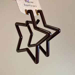 Star-shaped dark brown resin hoop earrings held in hand with card packaging display