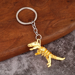 Makroaufnahme eines goldenen T-Rex-Skelett Schlüsselanhängers auf rustikalem Holzhintergrund