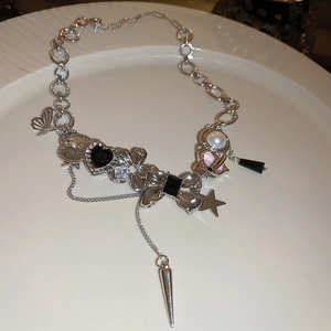 Detail of silver-tone chunky necklace with butterfly, heart, and star charms on a white plate