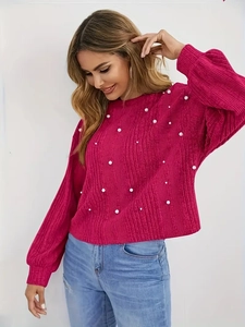 Détails de la texture côtelée et des perles blanches sur le pull en tricot fuchsia