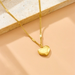 Gold plated stainless steel necklace with engraved heart pendant on a stone background