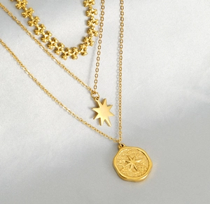 Detail of gold multi-layer necklace with star pendant and octagon coin on silk background