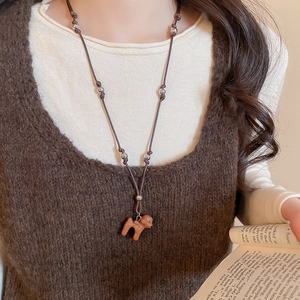 Détail du collier pendentif chiot marron avec cordon tressé porté sur un gilet en maille