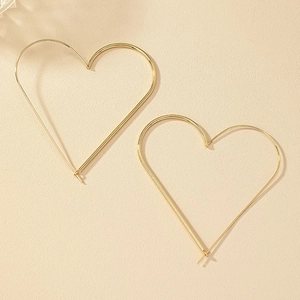 Detailed view of minimalist gold heart hoop earrings on a textured cream background