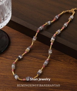 Dettaglio macro di perline in pietra naturale colorata e tubi dorati su collana boho