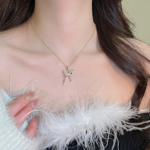 Macro detail of a gold butterfly necklace with green gemstone and clear zircons on model