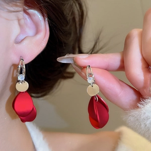 Detailed view of red acrylic petal earrings with zirconia accents worn by a model