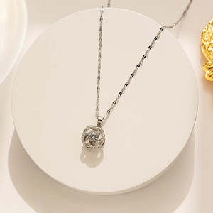 Detailed view of silver rotating camellia pendant with clear cubic zirconia on pedestal