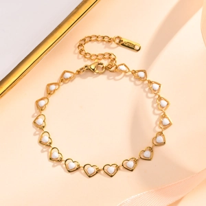 Detail of gold-plated stainless steel heart bracelet with white enamel inlay and lobster clasp