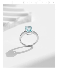 Macro view of a rectangular light blue gemstone set in a silver 925 band with accent stones