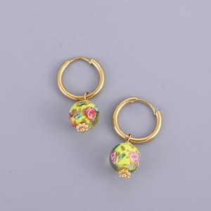 Detail of gold hoops with yellow floral porcelain heart pendants in vintage style