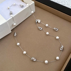 Detail of vintage pearl necklace with silver abstract face charms on display tray