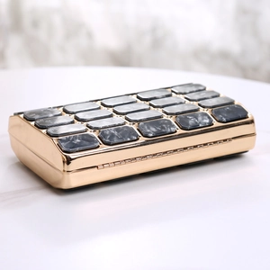 Detail view of acrylic evening clutch with gold metal frame and marble patterned tiles