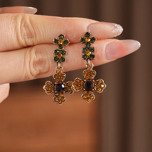Gros plan sur des boucles d'oreilles croix en bronze avec pierres orange et vertes