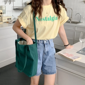 Deep green canvas tote bag styled with a yellow graphic T-shirt and denim shorts