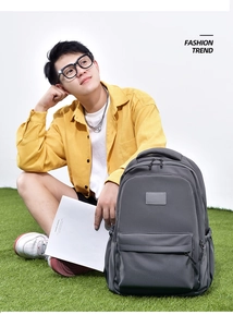 Detail of grey canvas backpack with front zip pocket on male model in casual park setting