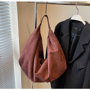 Detail view of large dark red suede tote bag hung next to a black stylish blazer