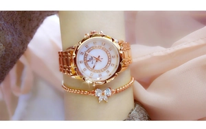 Close-up of rose gold women's watch and bow bracelet set with sparkling rhinestones
