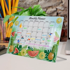 Detail of acrylic monthly planner featuring tropical fruit design and metal desk stand