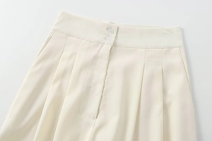 Détail du pantalon beige à taille haute montrant la fermeture à double boutonnage