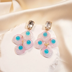 Détail des boucles d'oreilles en nacre rose avec strass sur un fond de soie élégant