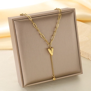 Détail du collier en Y doré avec pendentif cœur texturé sur fond de soie élégant
