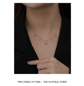 Detail of 925 sterling silver star and moon necklace on a model wearing black