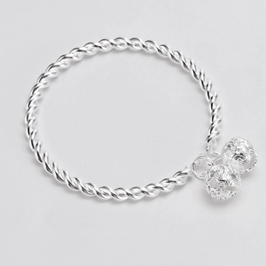 Detail view of silver twisted bangle featuring two hollow bell charms in high-quality finish