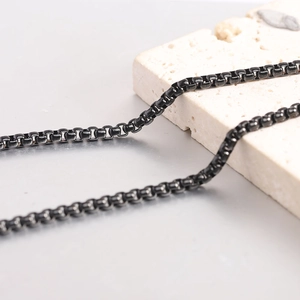Gros plan d'un collier chaîne box en acier titane noir avec pierre texturée élégante