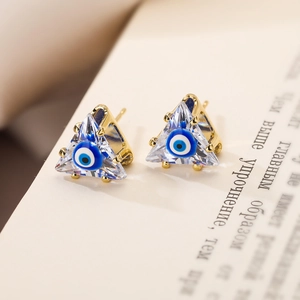 Nahaufnahme der vergoldeten Dreieck-Ohrstecker mit blauem Auge und klarem Zirkonia-Stein