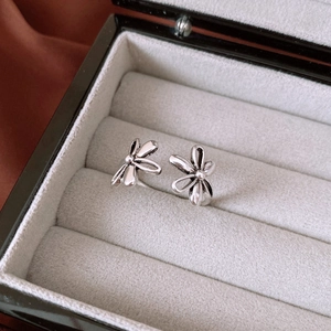 Detailed close-up of vintage silver floral stud earrings on a grey velvet jewelry box display