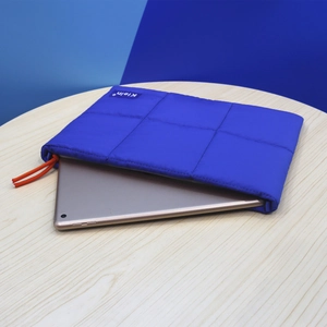 Detail of blue quilted space cotton laptop sleeve with soft texture and side orange knot