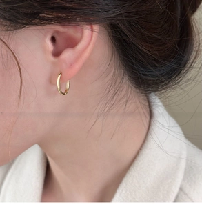Primo piano di una modella che indossa il piccolo orecchino a cerchio ovale placcato oro 18k