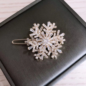 Detail of a rotating golden snowflake brooch with zircon crystals on a jewelry box