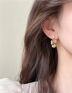 Détail de boucles d'oreilles grappe champagne avec finition dorée et perle sur mannequin